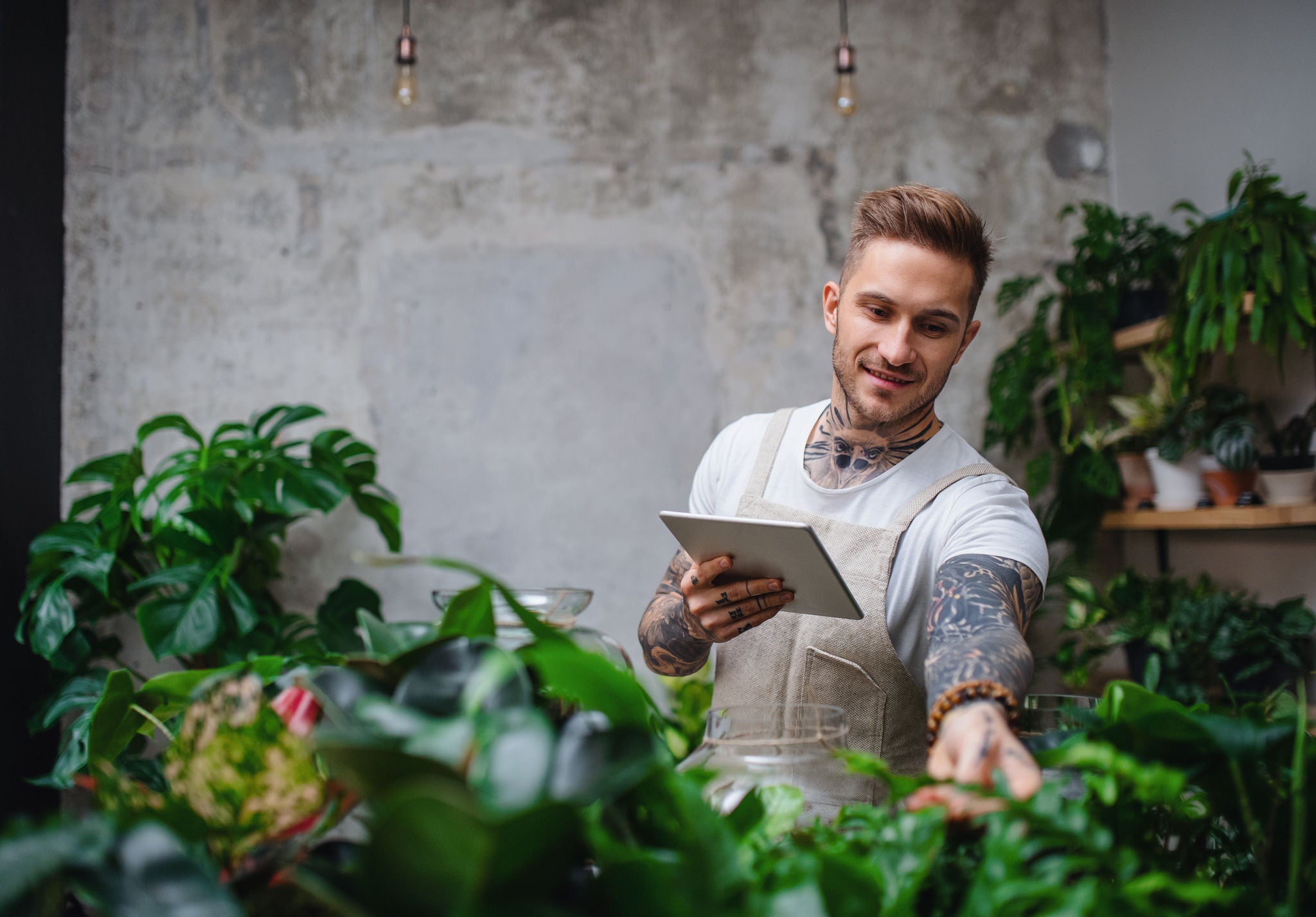 Man holding tablet while tending to some plants