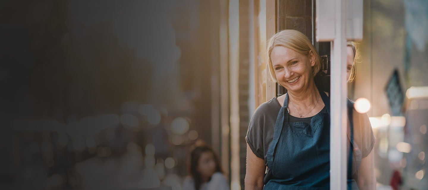 Confident female owner standing at entrance of deli.