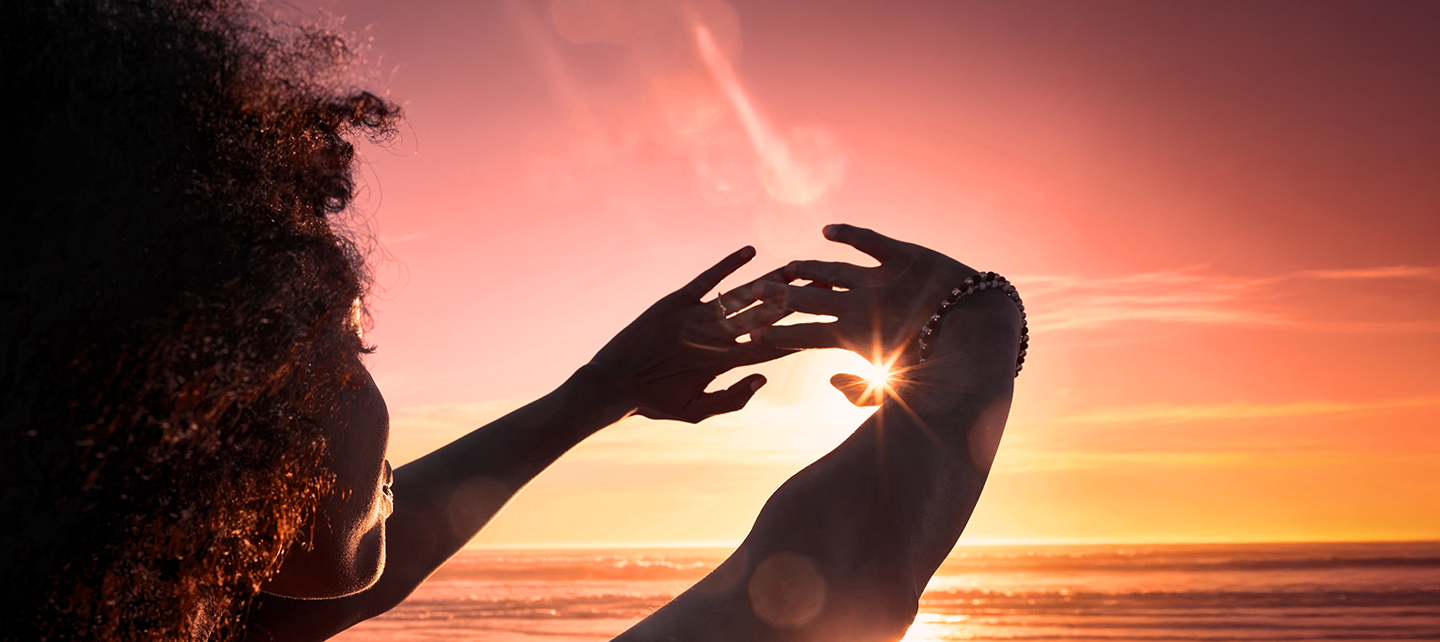 Woman framing the sun with her hands