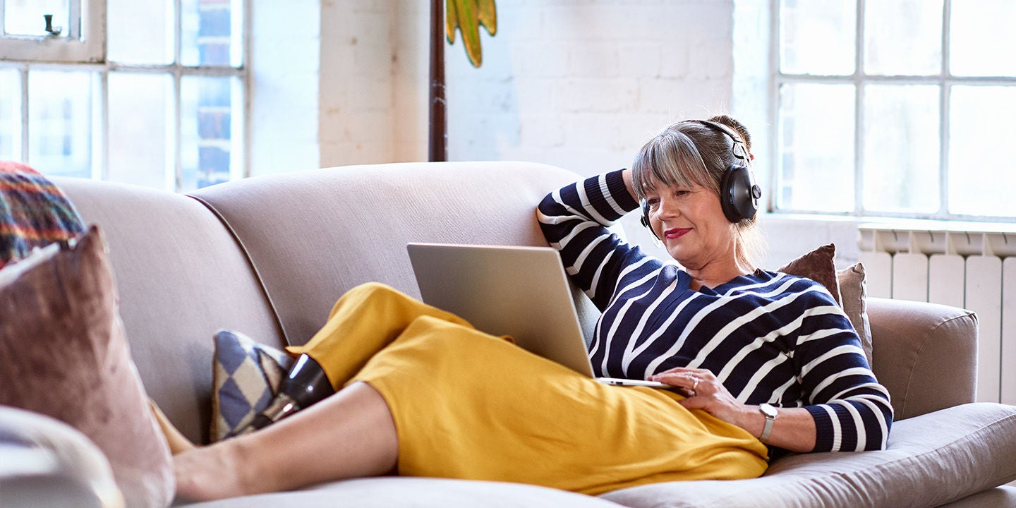 Woman laying on sofa using a laptop