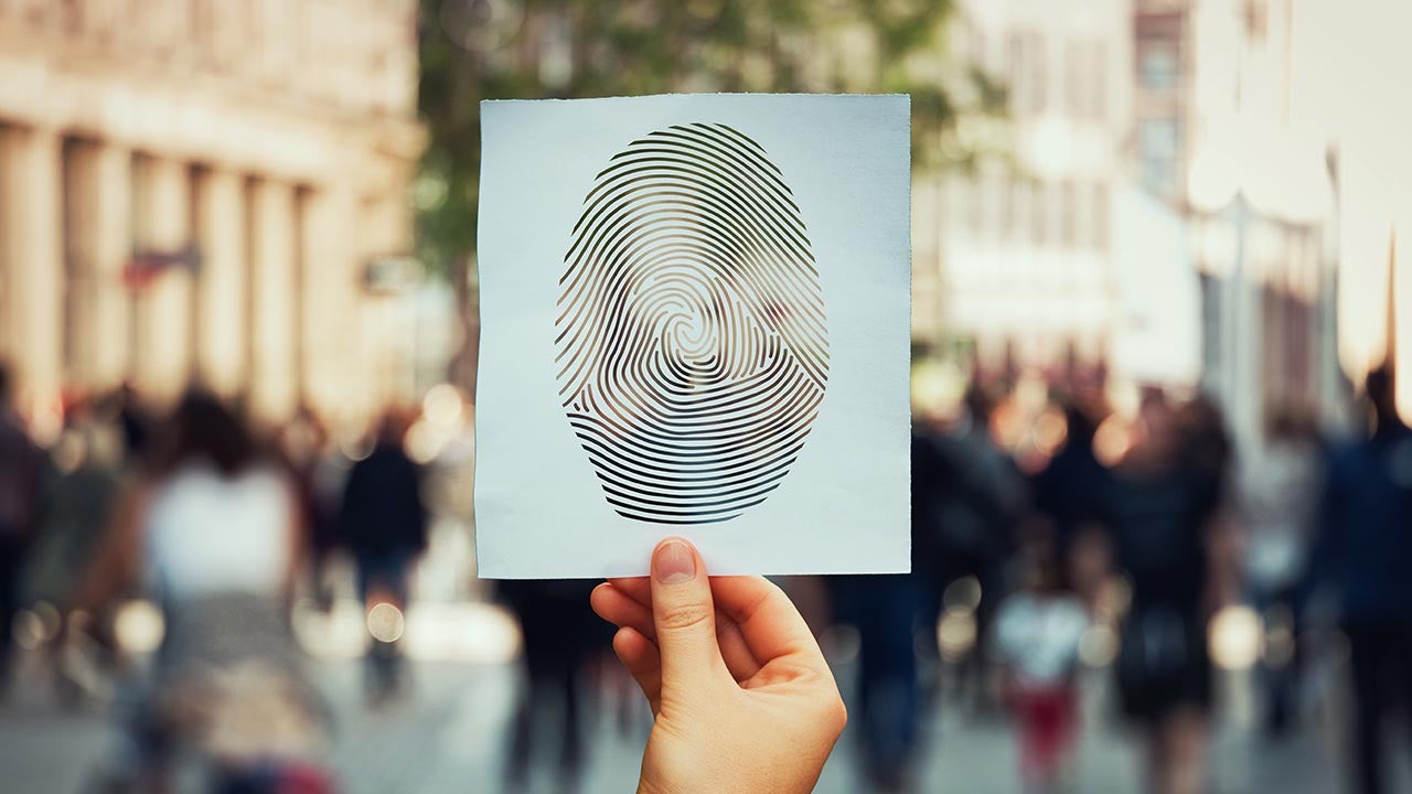 Holding paper with thumbprint among crowd to signal identity theft.