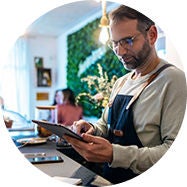 Small business person behind counter looking at tablet computer