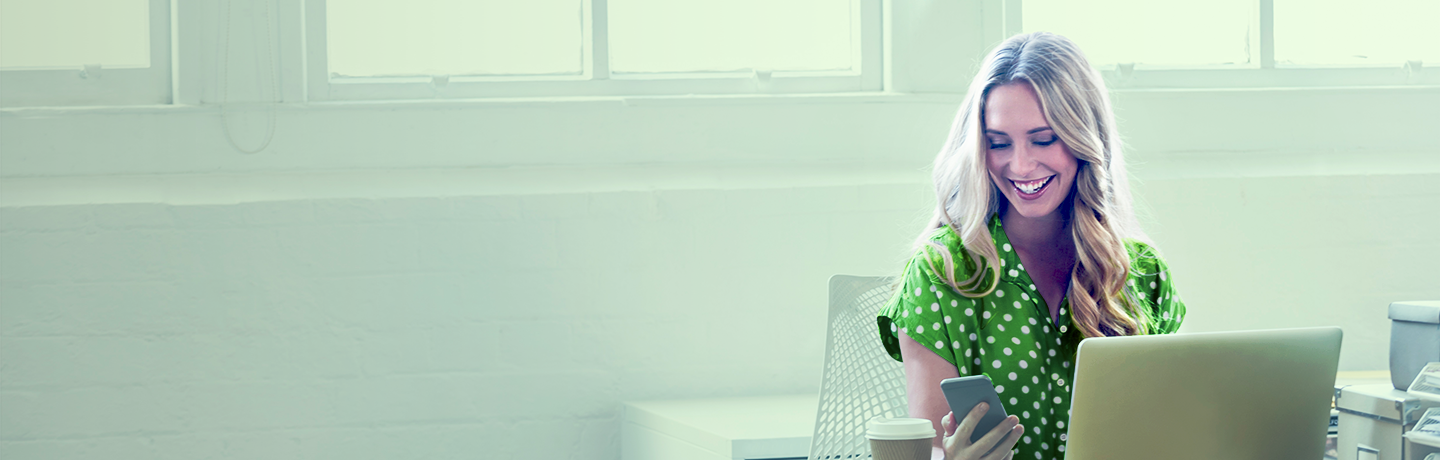 Женщина за столом, улыбающаяся компьютеру, просматривает открытый банкинг