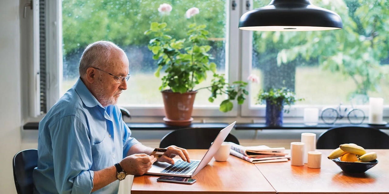 גבר מבצע תשלום מקוון במחשב הנייד בביתו
