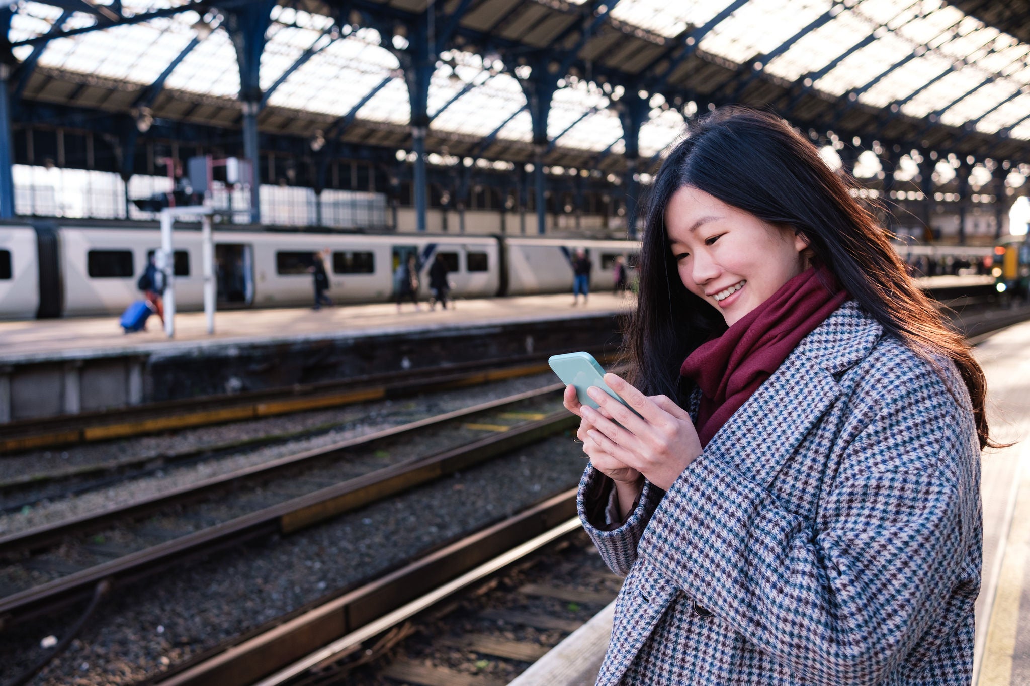 Woman smiling at phone waiting for train