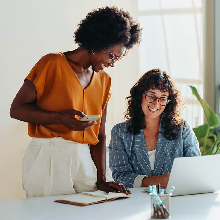 Two women smiling while looking at a computer
