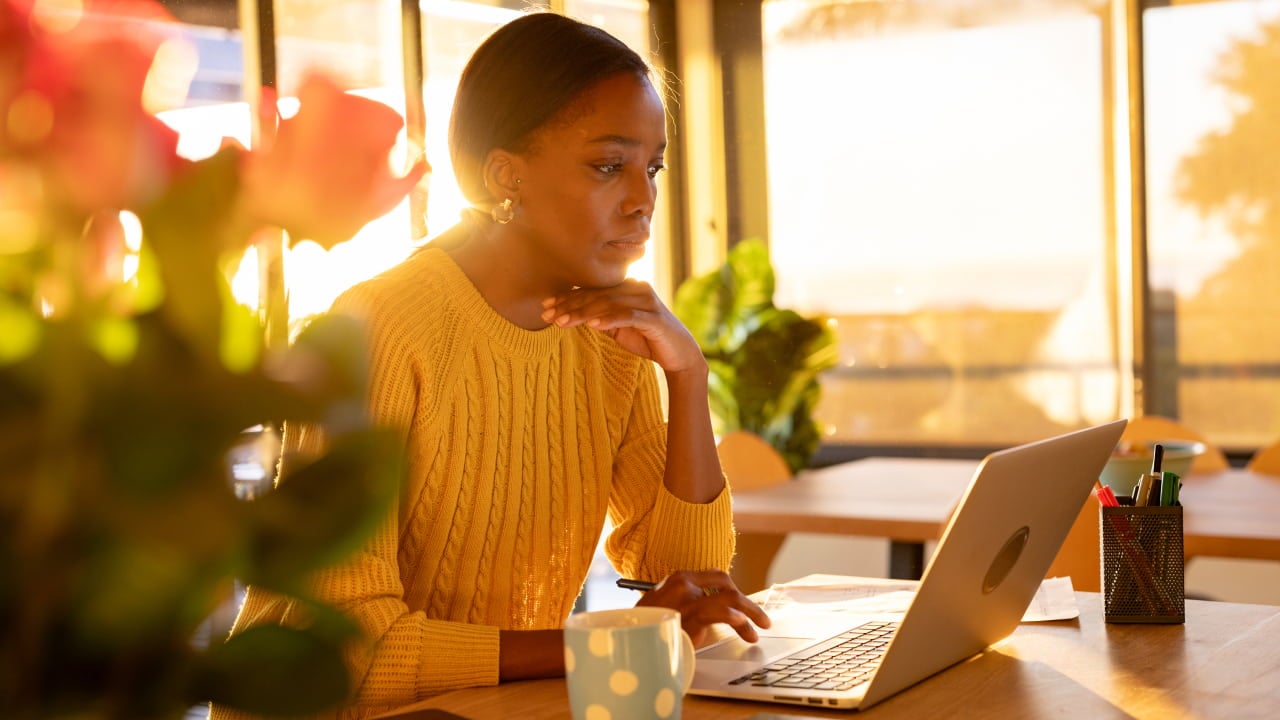 vrouw geconcentreerd aan het werk op haar laptop bij zonsondergang