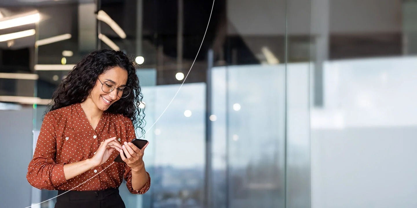 אשת עסקים משתמשת בטלפון במקום העבודה.