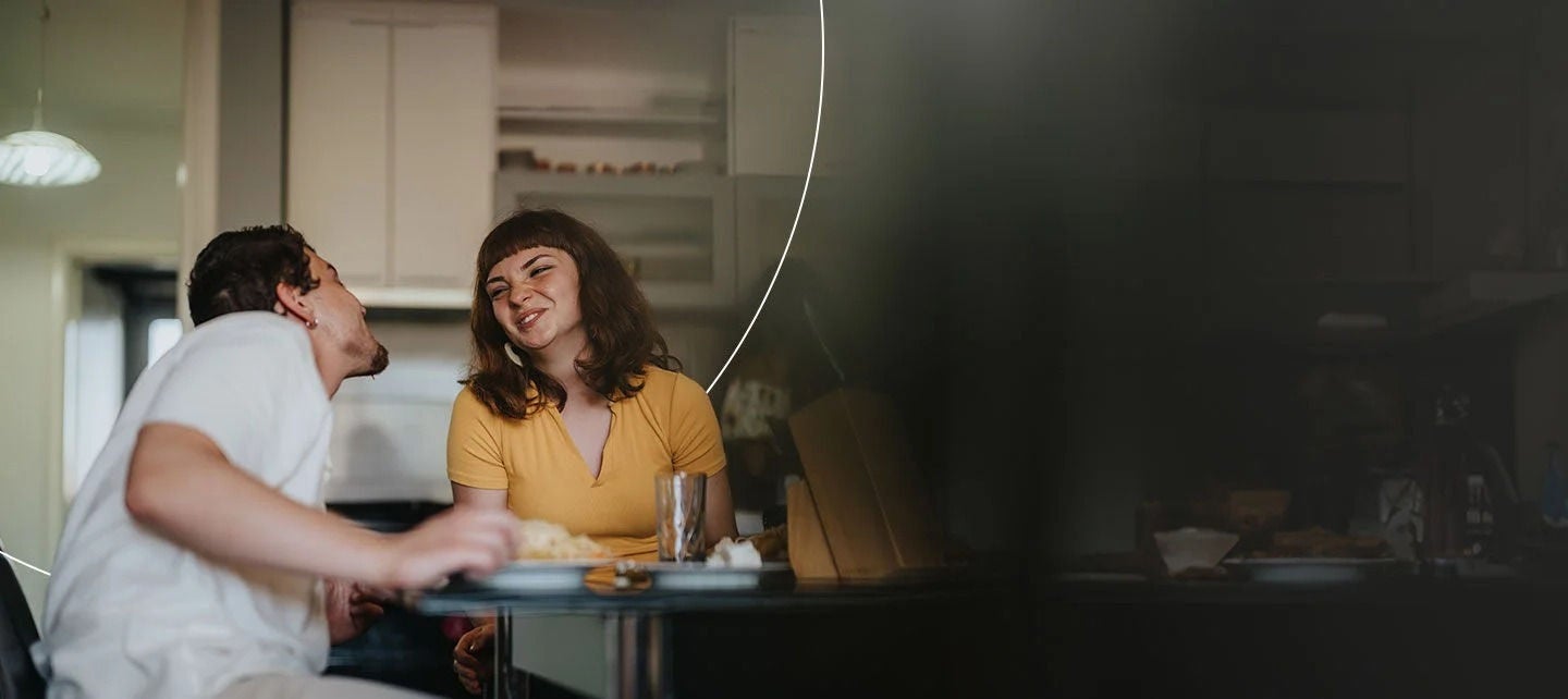 גבר ואישה יושבים ליד שולחן ומביטים זה בזה.