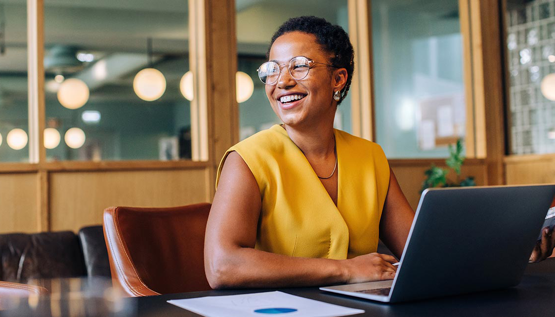 A woman looks to the side at her laptop