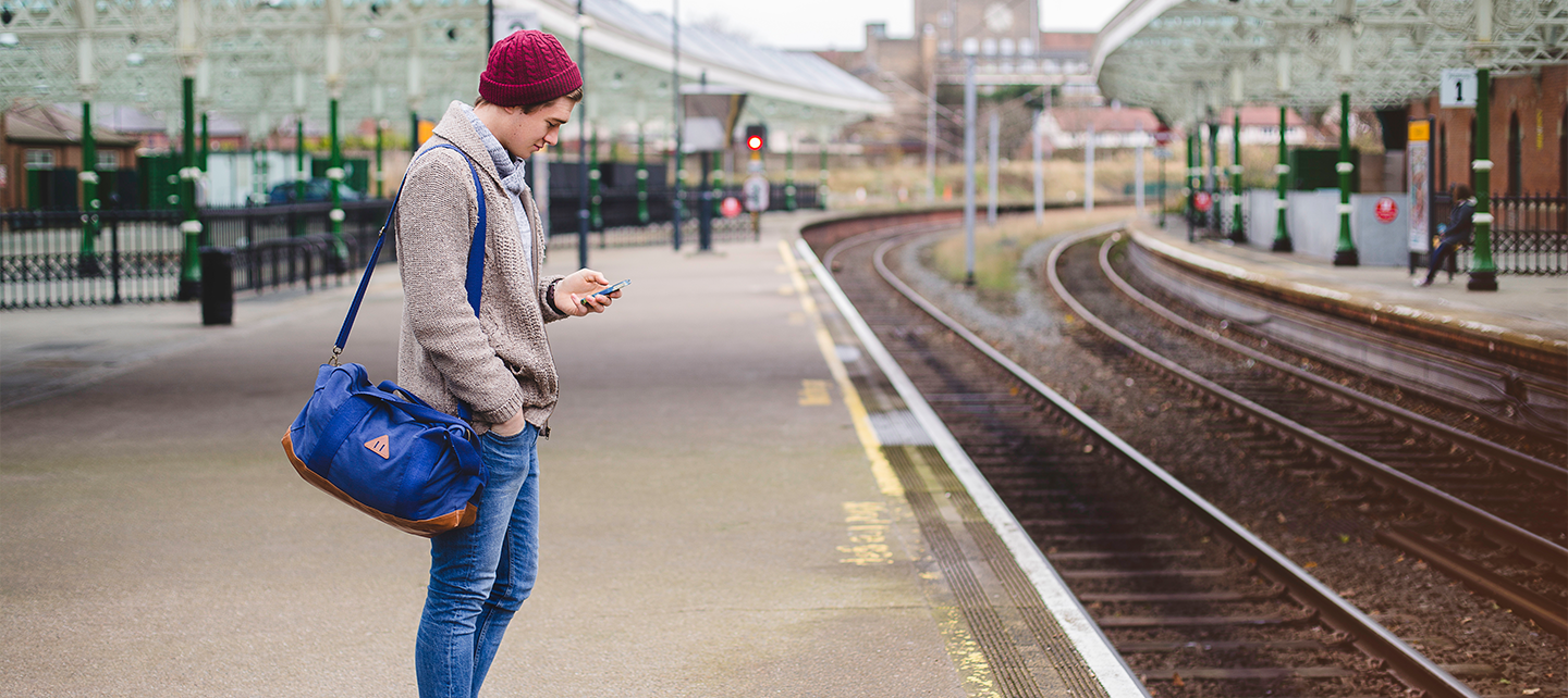 Man at a train station looking at phone