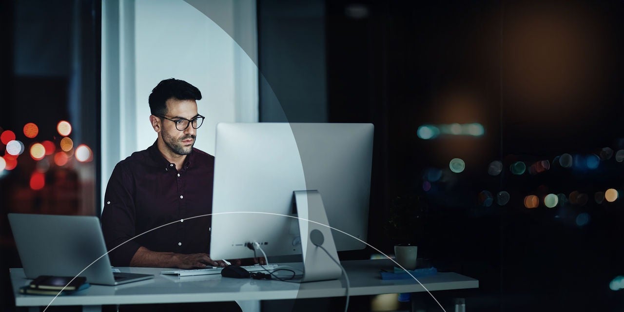 גבר יושב ליד שולחן עבודה מול מחשב.