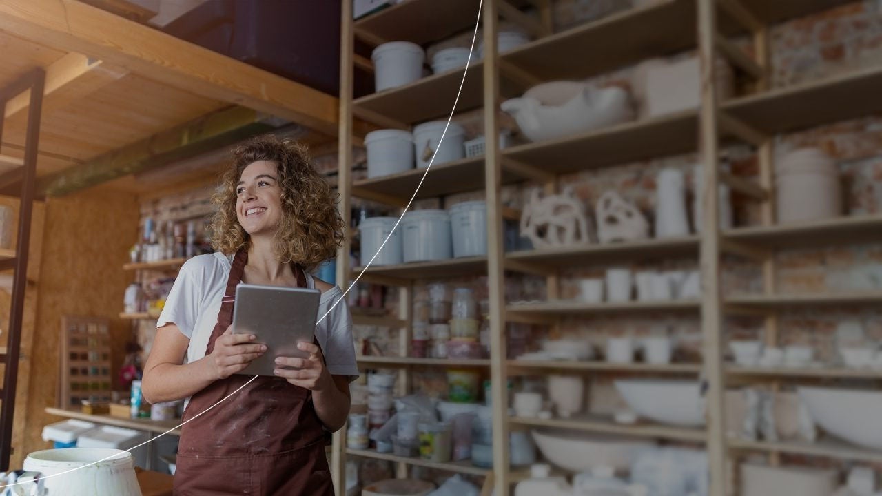 בעל עסק קטן מחייך, אוחז באייפד. 