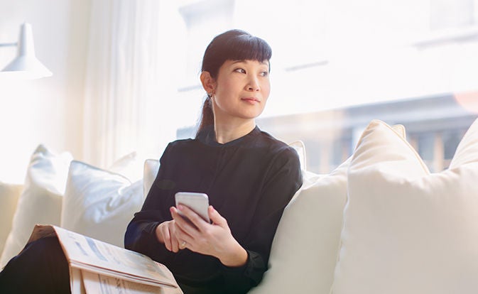 Woman sitting on a sofa holding a phone.