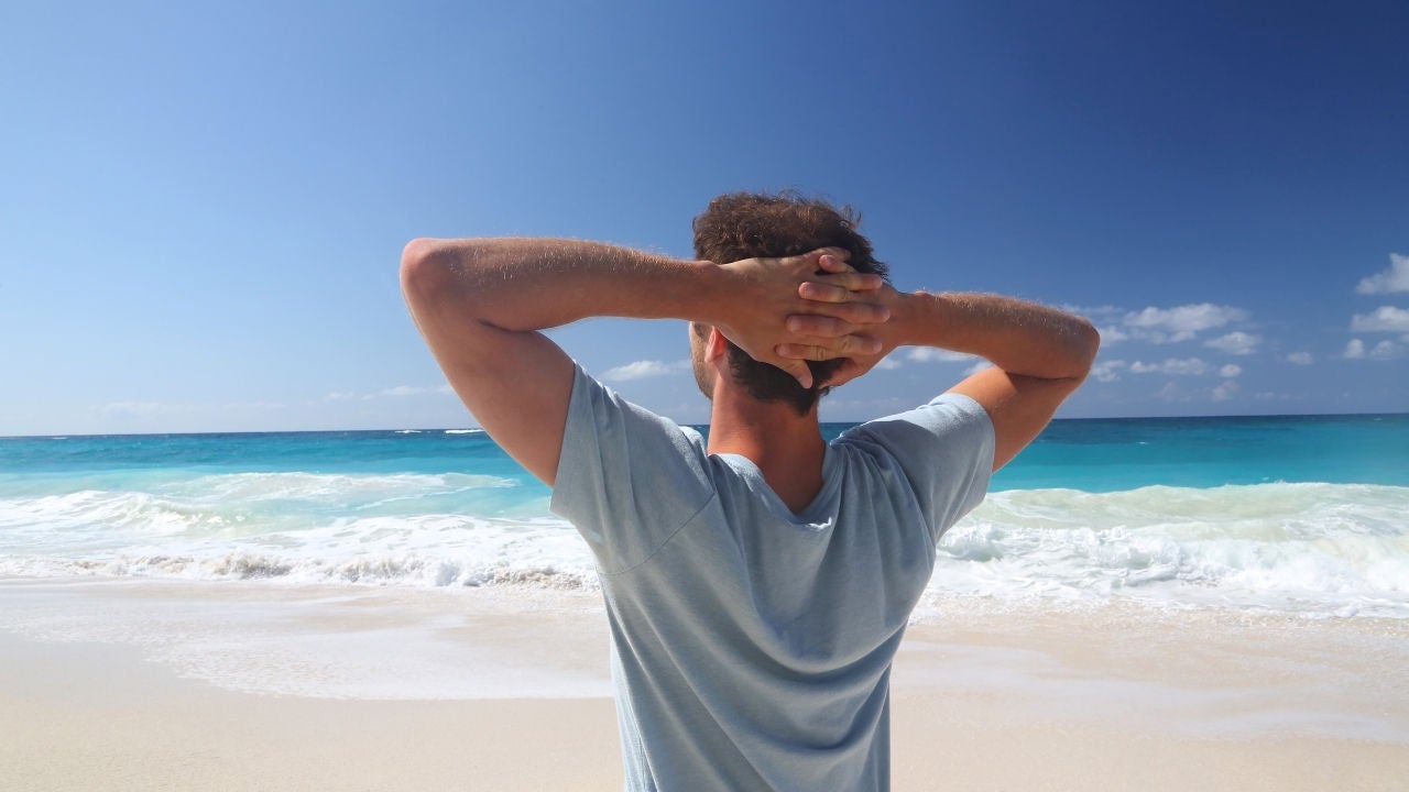 Man gazing out at the ocean from a beach.