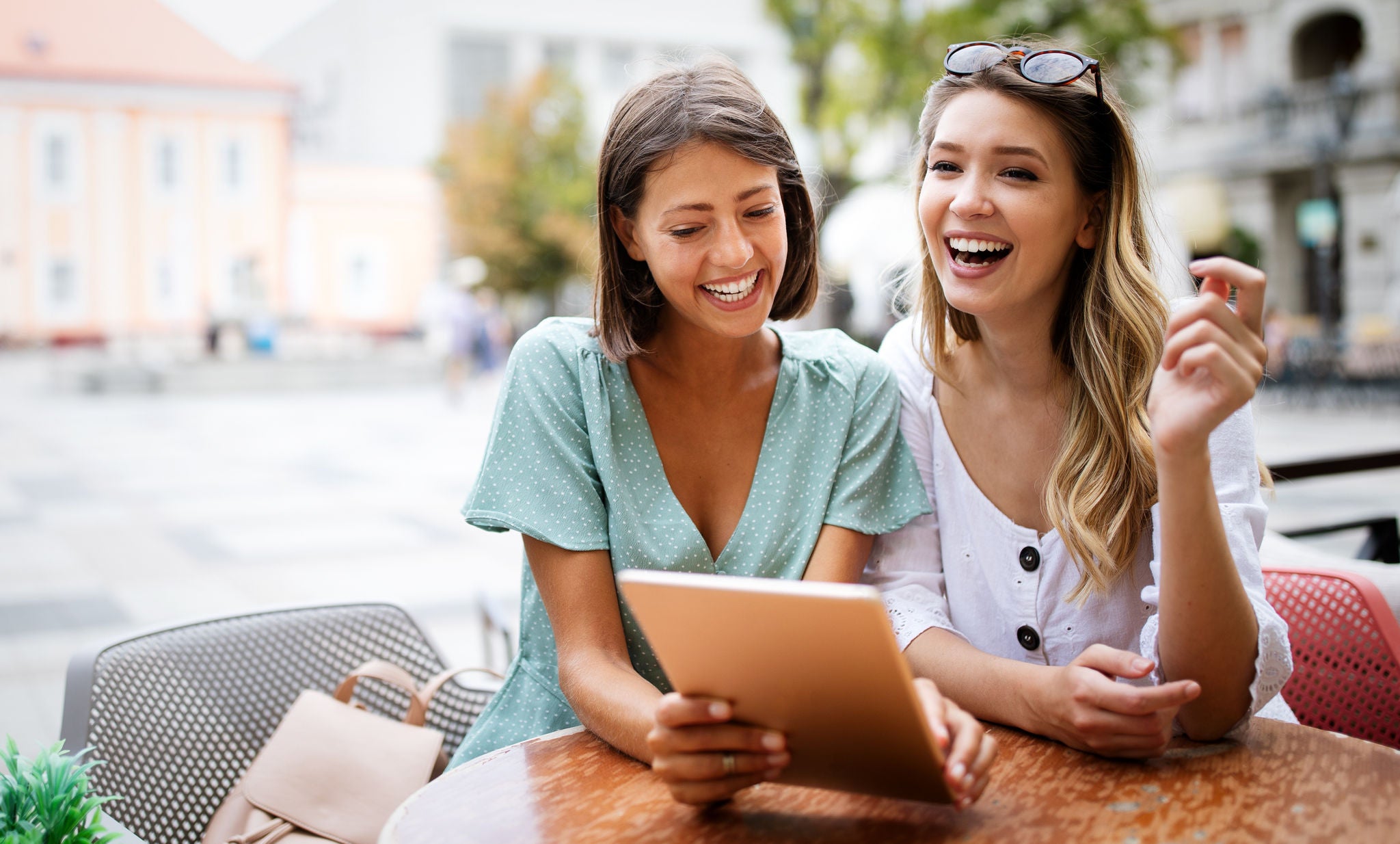 Prijateljice koriste tablet dok sjede u kafiću.