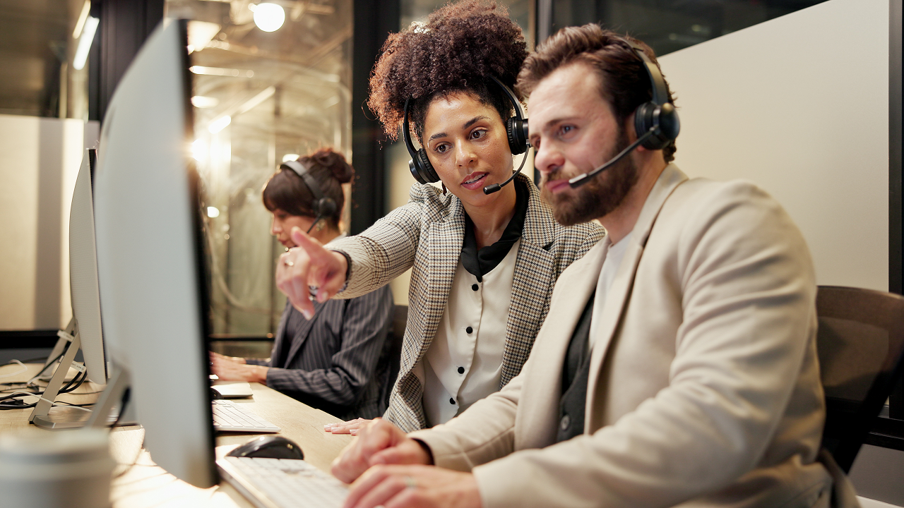 A man and woman sitting at a desk with a computer