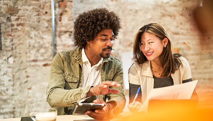 Businessman laughing with colleague while working together in coworking space