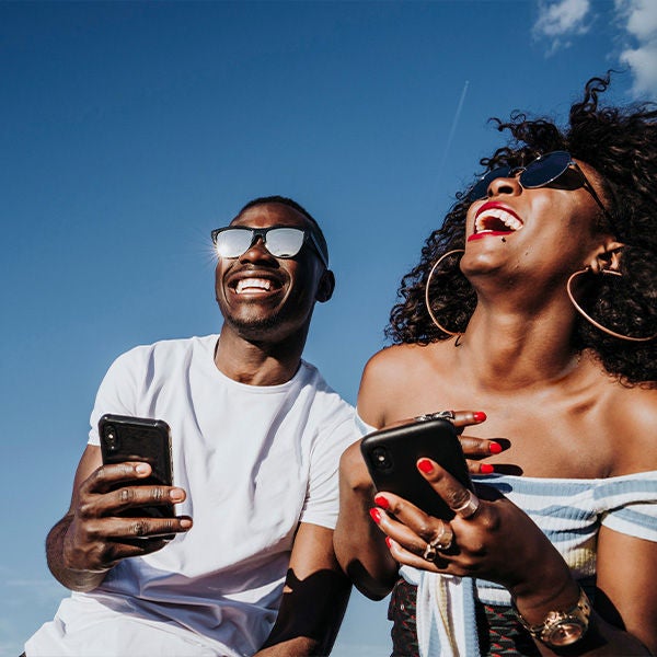 Happy man and woman laughing while looking at a phone