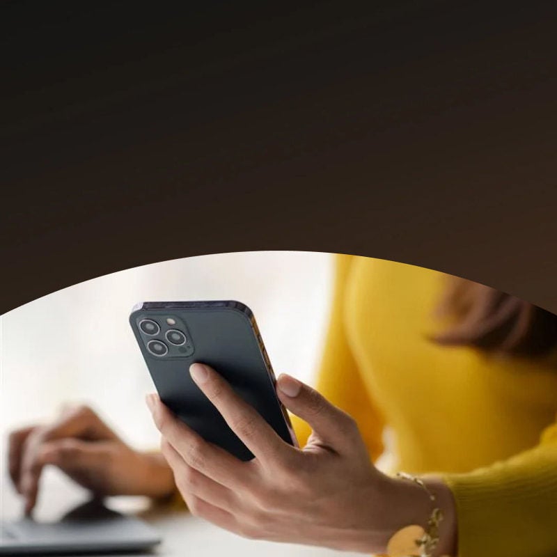 person holding smartphone while using laptop