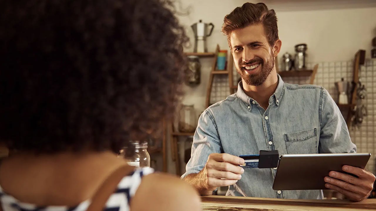 Man using tablet credit card reader in cafe.