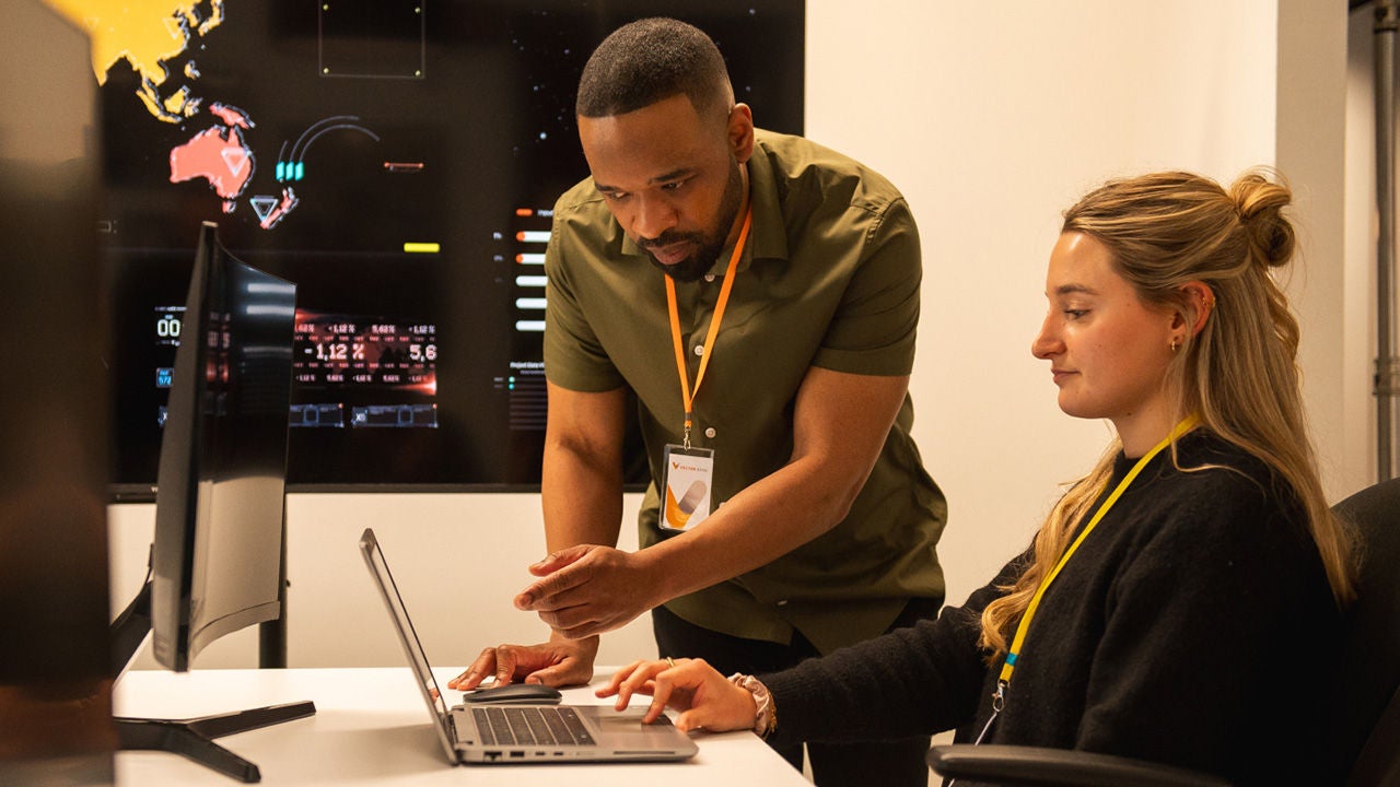Man assisting woman with data on laptop