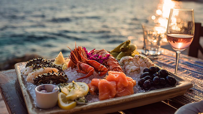 Appealing platter of fresh seafood with sea in backdrop.