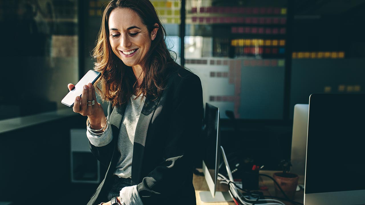 Woman in a dark office speaking into phone.