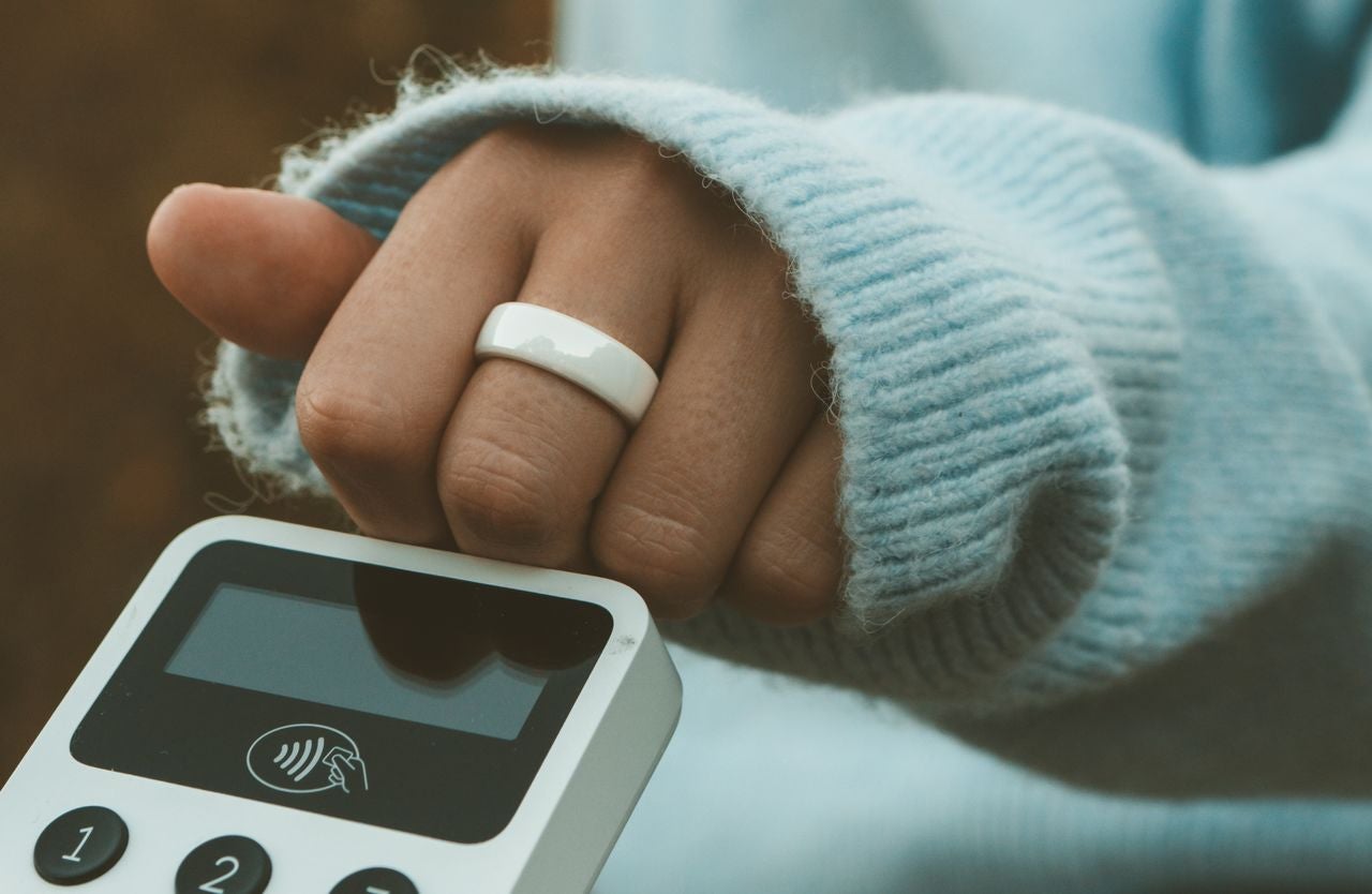 Nærbilde av en hånd med en betalingsring brukt for kontaktløse transaksjoner.