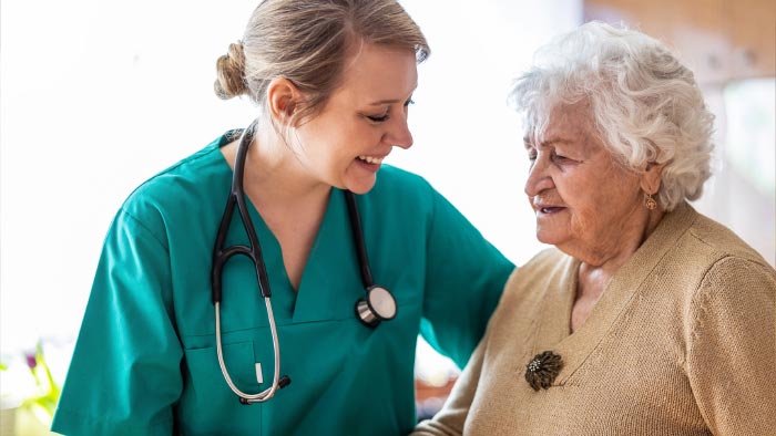 A nurse helping an elderly woman.