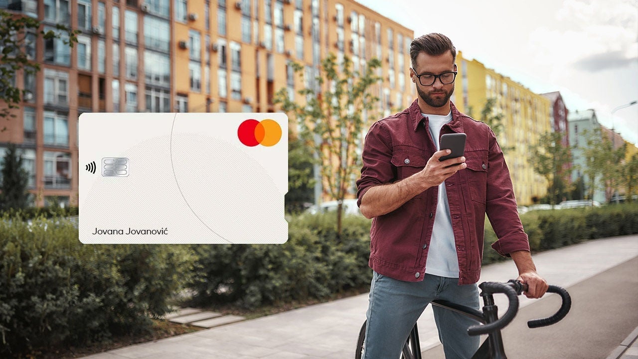 Čovek vozi bicikl i slika Mastercard kreditne kartice.