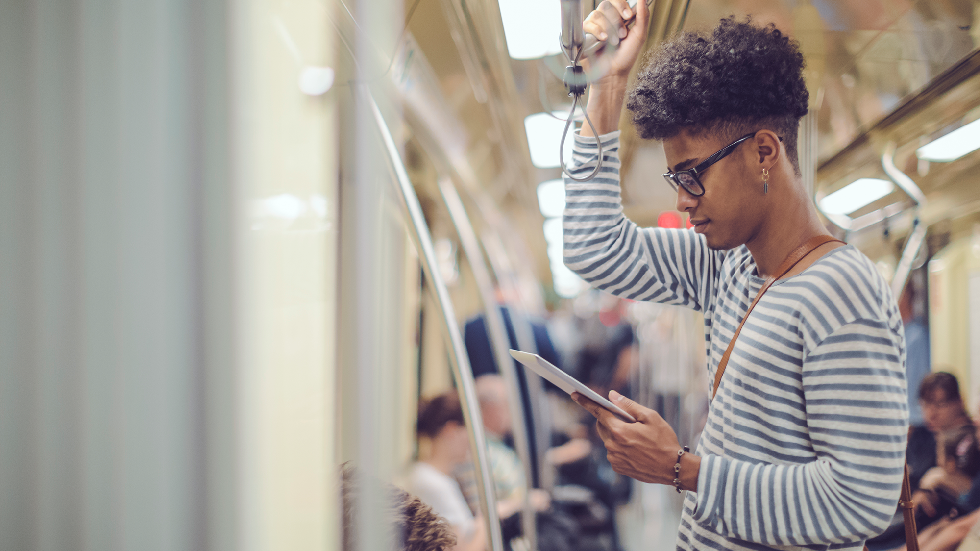 Man holding a tablet and standing on a subway train.