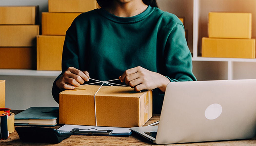Woman opening a gift in front of her laptop