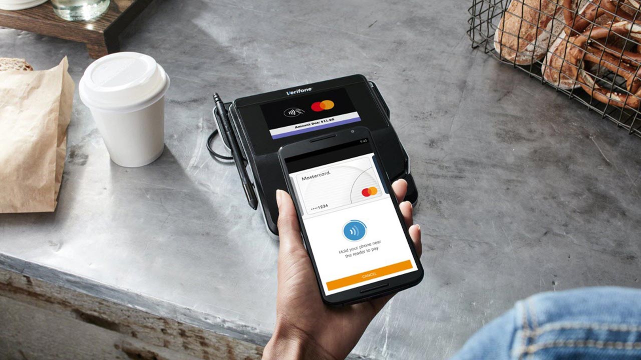 Close up of phone tapping payment terminal at coffee shop.