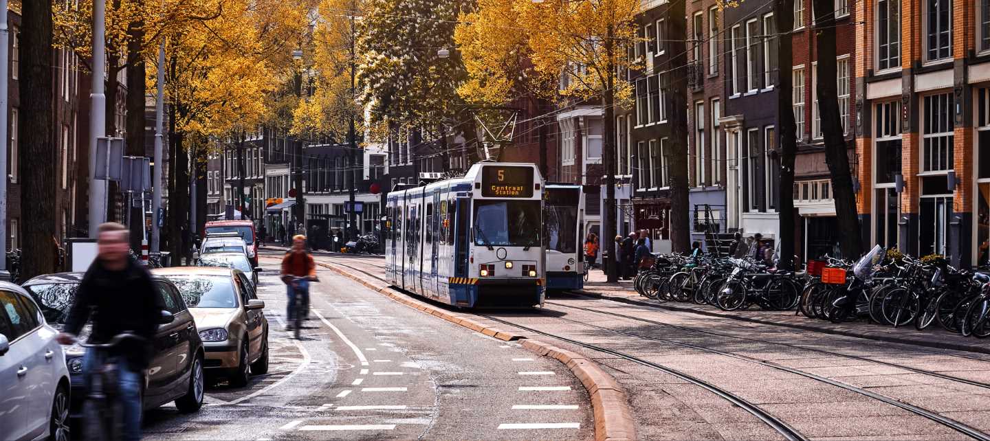 msterdam, Netherlands. Street view, Modern tram, public transport moving by Autumn evening sunny day. Bicycle on the road