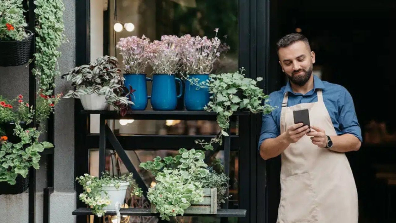 Fleuriste debout dehors avec son mobile