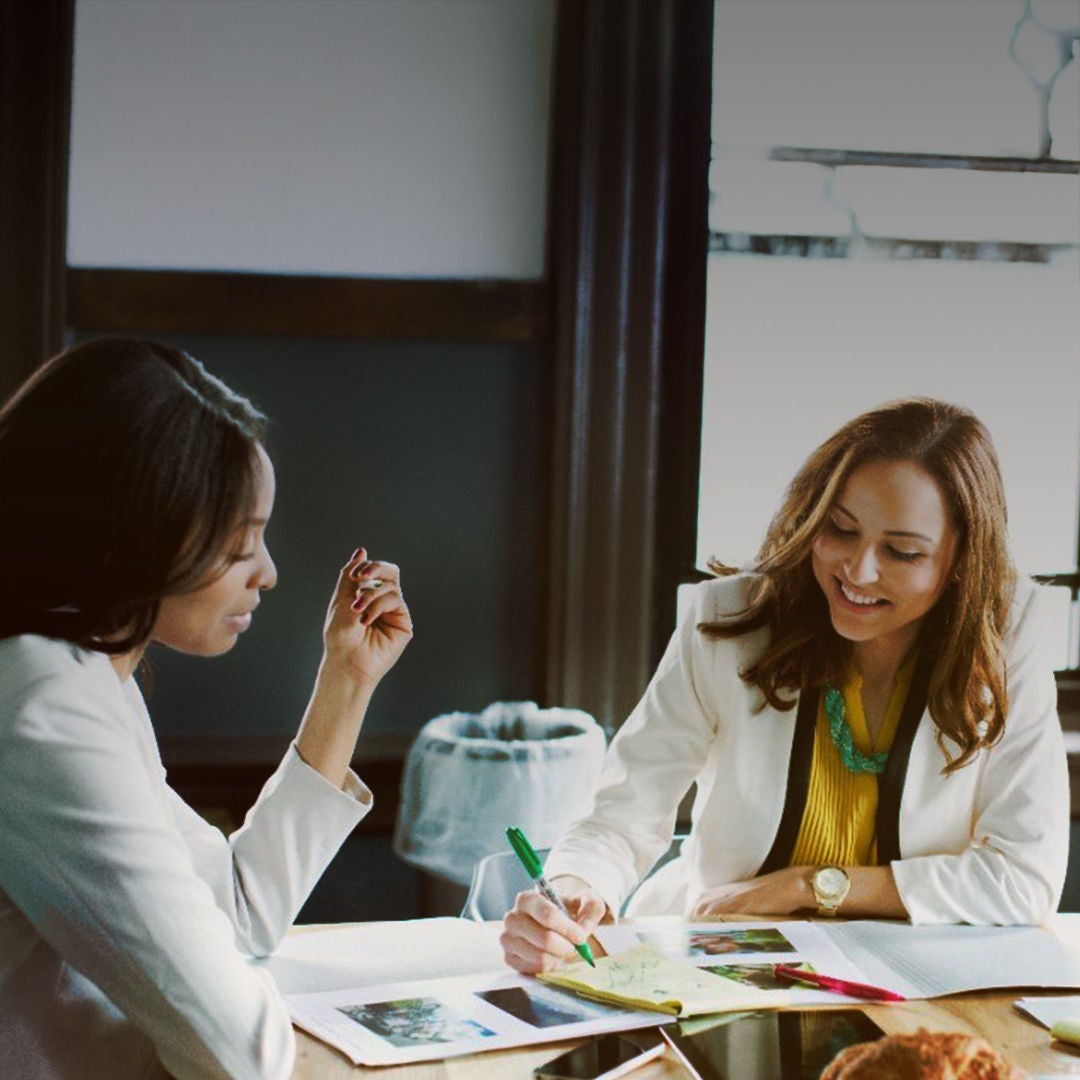 Two women engaged in conversation while sitting at a table, sharing a moment together.