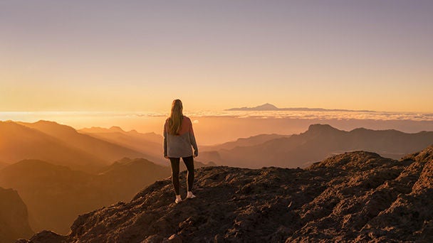 Woman on mountain top looking at sunset