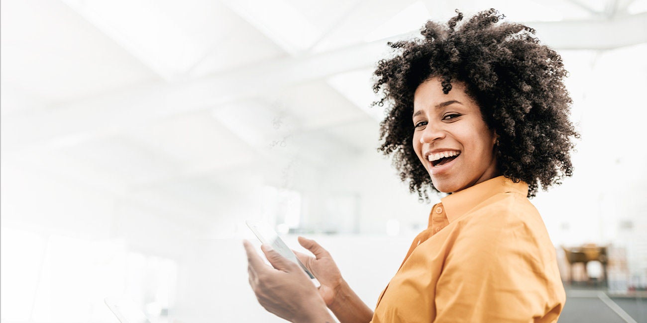 Person with phone and earbuds walking on a street.