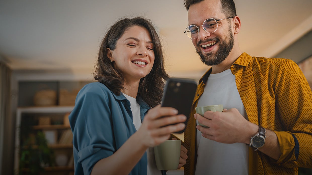 Two people looking at phone while having coffee. 