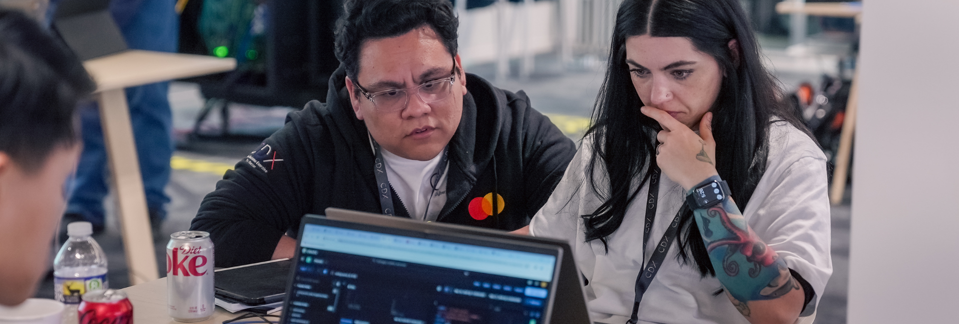 Two cybersecurity experts look at a laptop.