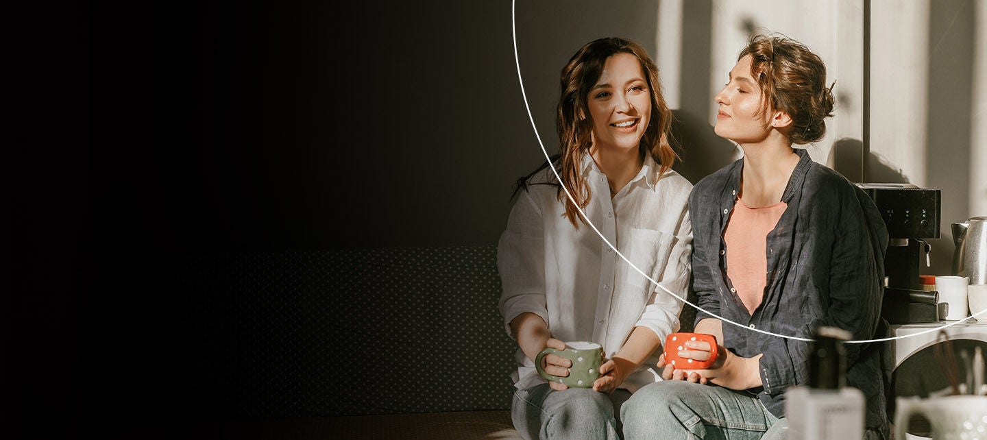 Žena se smeši gledajući nekoga pored sebe, okrenuta ka prozoru.