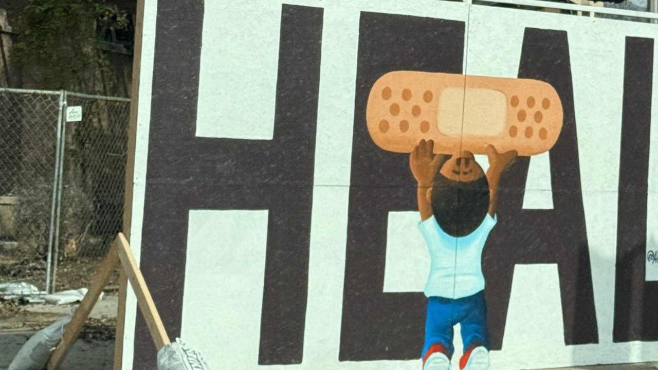A mural on a wall spelling out Heal with a child holding up a band-aid