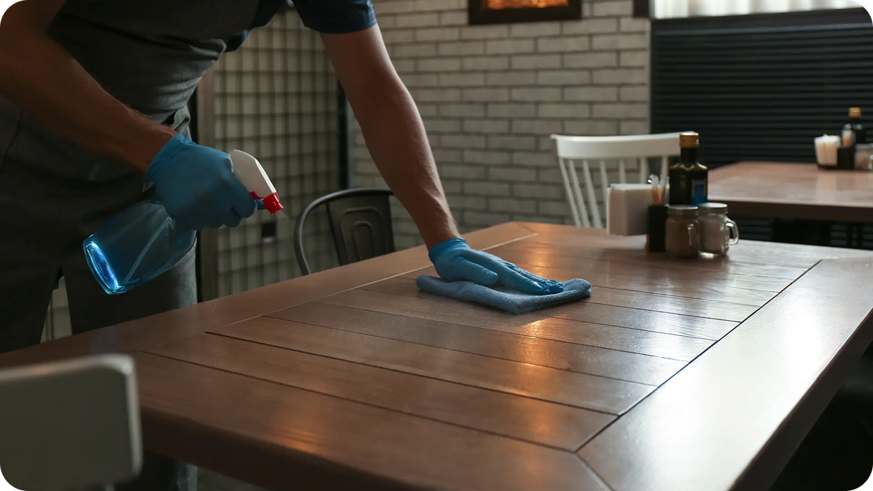 man is cleaning a table with cloth