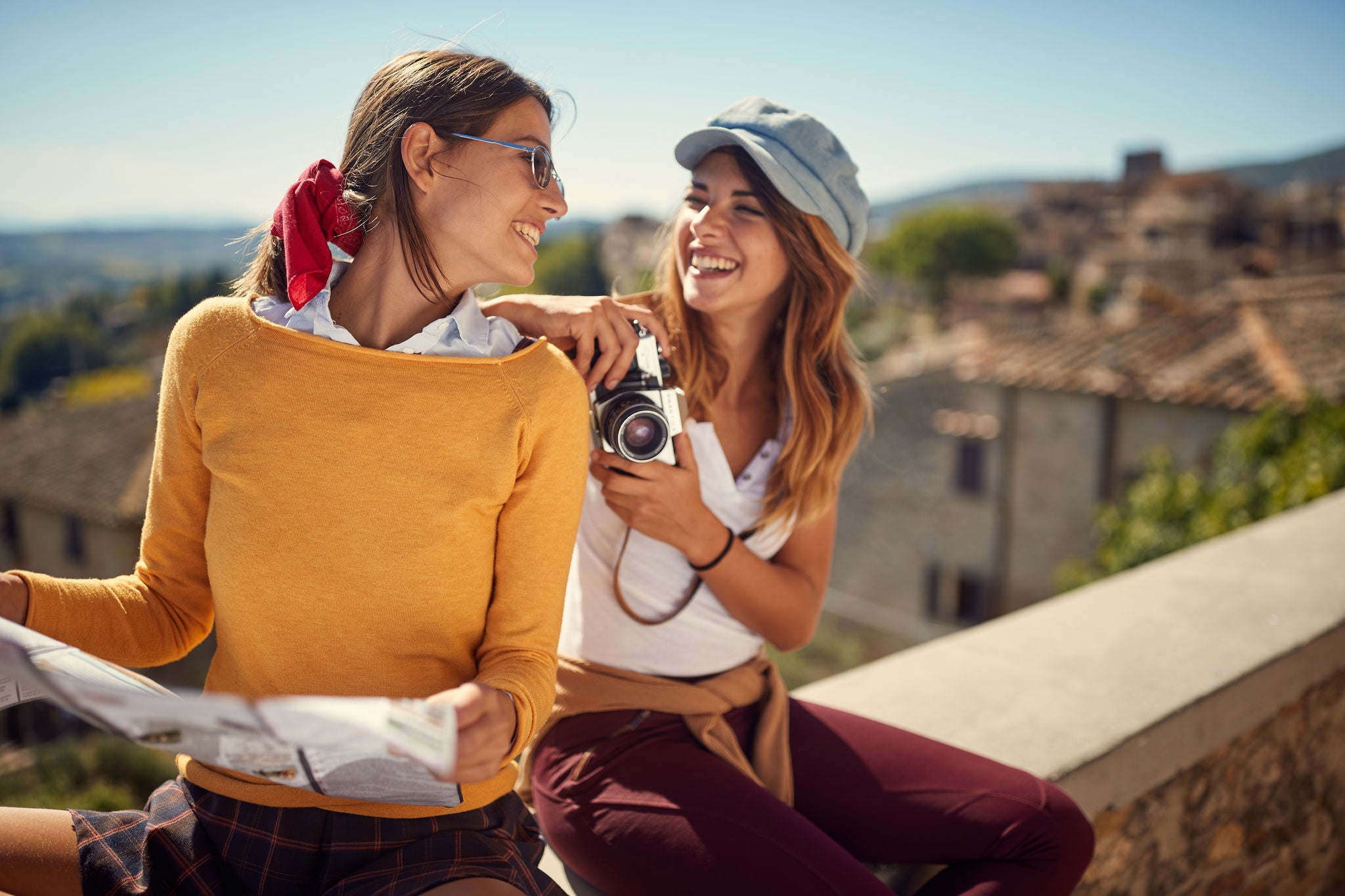 Prijateljice na putovanju gledaju u mapu i kameru.