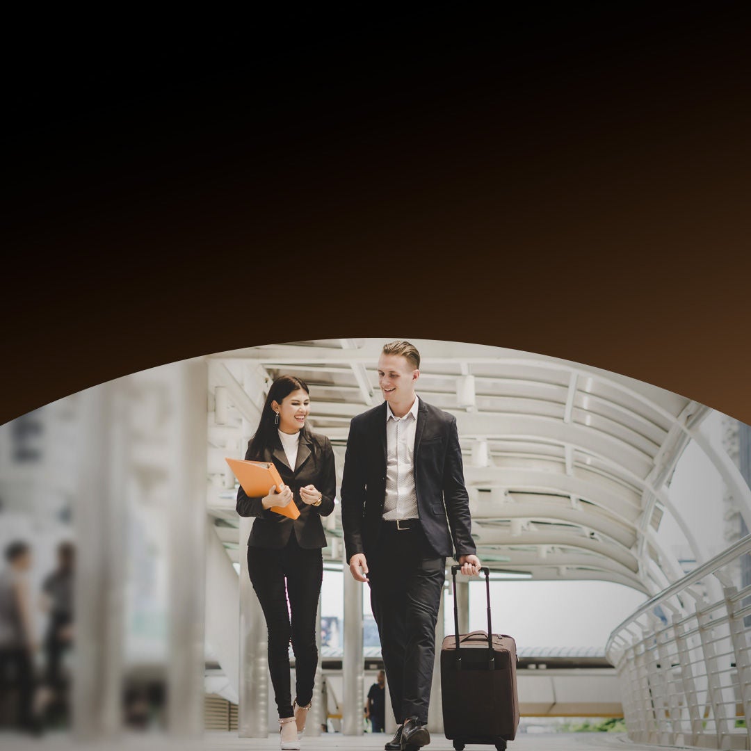 Two individuals walking with suitcases, suggesting travel or event organization.