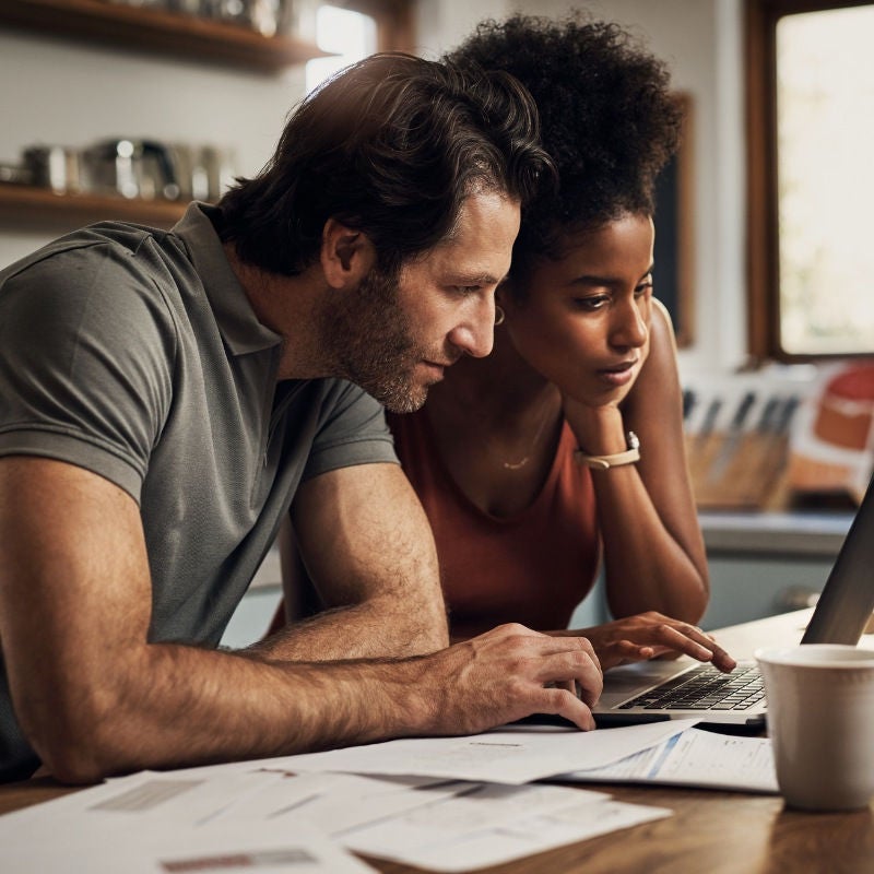 A couple look at their laptop in their kitchen.