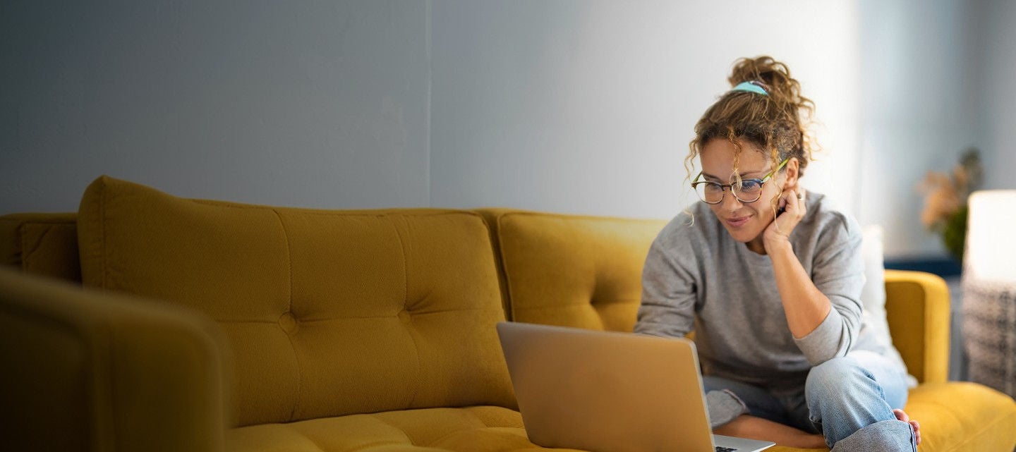 A woman sitting on a couch using a laptop
