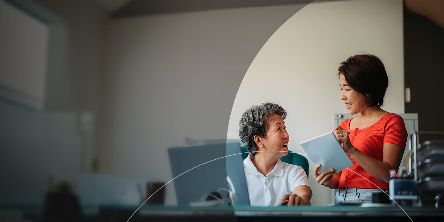 Two employees discussing bills with a notepad and a laptop.