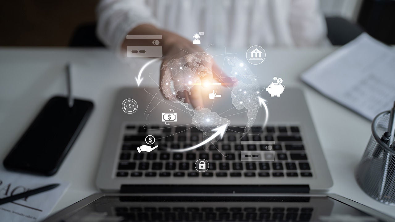 Hand over an open laptop with global and financial icons